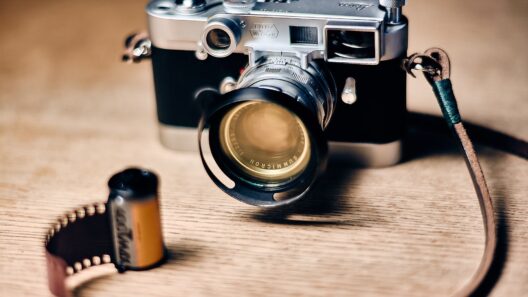 Eine klassische Leica-Kamera mit einem Nah-Summicron-Objektiv steht auf einem Tisch neben einer entwickelten Filmrolle.