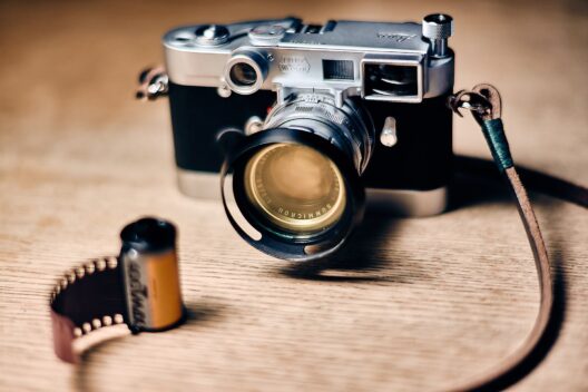 Eine klassische Leica-Kamera mit einem Nah-Summicron-Objektiv steht auf einem Tisch neben einer entwickelten Filmrolle.