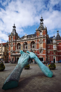 Eine beeindruckende Skulptur von Händen steht vor einem historischen Gebäude in Amsterdam