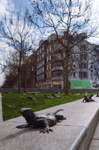 Bronzene Eidechsen in Amsterdam, umgeben von Bäumen und modernen Gebäuden. Schönes Beispiel der Variabilität einer Mandler Linse.