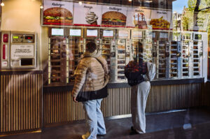 Zwei Personen stehen an einem Selbstbedienungsautomaten in Amsterdam und wählen Burger und Snacks aus | © Stefan Groenveld.