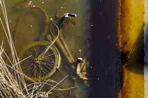 Ein Fahrrad liegt schon leicht vermost im Wasser