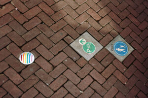 Bunte Straßenmarkierungen auf dem gepflasterten Boden in Amsterdam weisen auf Fußgänger- und Radwege hin.
