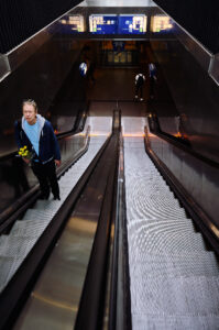Ein Mann mit Blumen steht auf der Rolltreppe in einem modernen U-Bahnhof in Amsterdam.