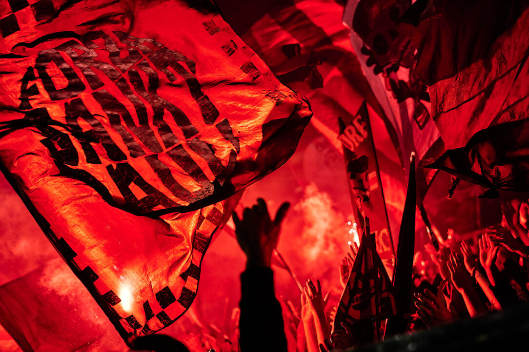 Fahnenschwenkende Fans des FC St. Pauli feiern in einem leuchtend roten Stadion mit Leidenschaft und Energie.